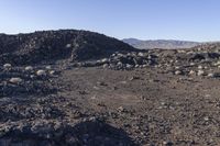 a pile of rocks in the middle of a barren area with many small rocks around