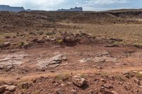 a dirt field that has rocks and mountains in the background at a scenic overlook in arizona