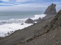 the waves hit rocks near the shore of the water's edge and crash on it