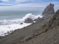 the waves hit rocks near the shore of the water's edge and crash on it