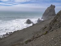 the waves hit rocks near the shore of the water's edge and crash on it