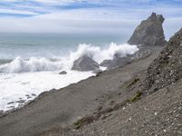 the waves hit rocks near the shore of the water's edge and crash on it