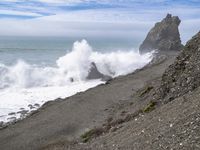 the waves hit rocks near the shore of the water's edge and crash on it