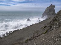 the waves hit rocks near the shore of the water's edge and crash on it