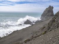 the waves hit rocks near the shore of the water's edge and crash on it