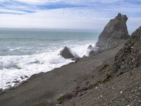 the waves hit rocks near the shore of the water's edge and crash on it