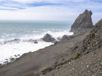 the waves hit rocks near the shore of the water's edge and crash on it