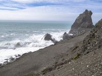 the waves hit rocks near the shore of the water's edge and crash on it