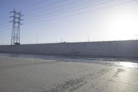 water flowing down the road behind large poles and electrical lines against a clear blue sky