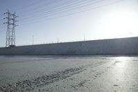 water flowing down the road behind large poles and electrical lines against a clear blue sky