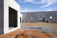 the cement building is constructed with two walls under construction and there are some bars attached