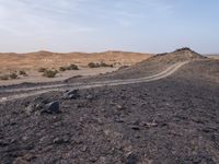 a truck on a dirt road in the desert with rocks and stones on the ground