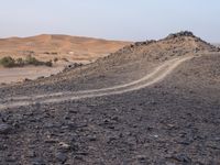 a truck on a dirt road in the desert with rocks and stones on the ground