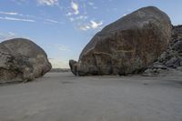 there are two large rocks on the ground in the desert between them is a rock and some blue sky