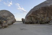 there are two large rocks on the ground in the desert between them is a rock and some blue sky