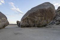 there are two large rocks on the ground in the desert between them is a rock and some blue sky