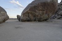 there are two large rocks on the ground in the desert between them is a rock and some blue sky