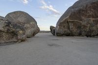 there are two large rocks on the ground in the desert between them is a rock and some blue sky