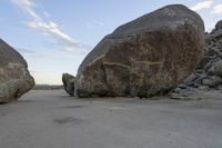 there are two large rocks on the ground in the desert between them is a rock and some blue sky