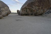 there are two large rocks on the ground in the desert between them is a rock and some blue sky