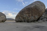 there are two large rocks on the ground in the desert between them is a rock and some blue sky