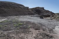 an abandoned hillside area is dotted with dirt and grass and a small patch of grass growing in between rocks