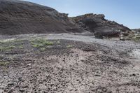 an abandoned hillside area is dotted with dirt and grass and a small patch of grass growing in between rocks