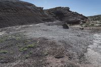 an abandoned hillside area is dotted with dirt and grass and a small patch of grass growing in between rocks