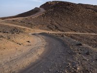 a truck on a dirt road in the desert with rocks and stones on the ground