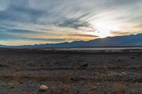 a person is on their bike in the desert at sunset with mountains behind them and a sky with clouds