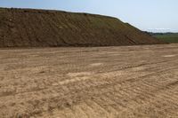 this large hill is surrounded by dirt on a clear day there is an image of dirt mound on the side