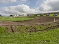 an image of a dirt track during the day time in the country back yard with a small section of the grass at the side that is a long edge of the field