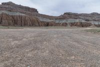 an empty field next to a big mountain with rocks in the background of the picture