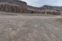 an empty field next to a big mountain with rocks in the background of the picture