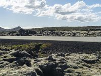 the asphalt in the center of the landscape is covered with licheny rocks, as the road goes below