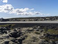 the asphalt in the center of the landscape is covered with licheny rocks, as the road goes below