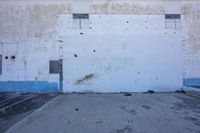 an empty parking lot and building with a skateboard propped up against the wall,