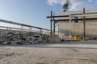 large pile of stones sitting next to building under construction crane and equipment with blue sky in the background