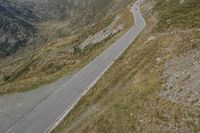 a motorcycle parked on a small mountain side road near mountains with no cars driving on it