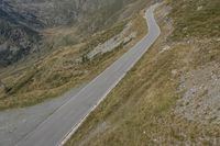 a motorcycle parked on a small mountain side road near mountains with no cars driving on it