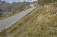 a motorcycle parked on a small mountain side road near mountains with no cars driving on it