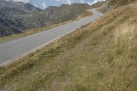 a motorcycle parked on a small mountain side road near mountains with no cars driving on it