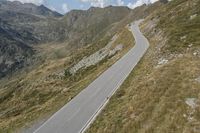 a motorcycle parked on a small mountain side road near mountains with no cars driving on it