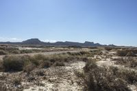 an empty road in a wide open plain of land near mountains and water on a sunny day