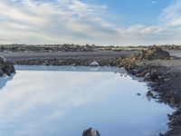 a blue body of water with rocks around it on the shore of an island with some water in it