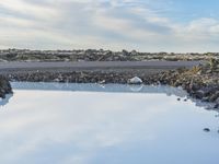 a blue body of water with rocks around it on the shore of an island with some water in it