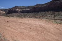 a motorcycle parked in an arid area near mountains and dirt road tracks in the desert