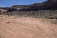 a motorcycle parked in an arid area near mountains and dirt road tracks in the desert