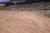 a motorcycle parked in an arid area near mountains and dirt road tracks in the desert