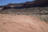 a motorcycle parked in an arid area near mountains and dirt road tracks in the desert